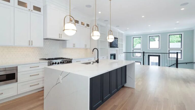 Modern kitchen with white cabinets, island, and hardwood floors.