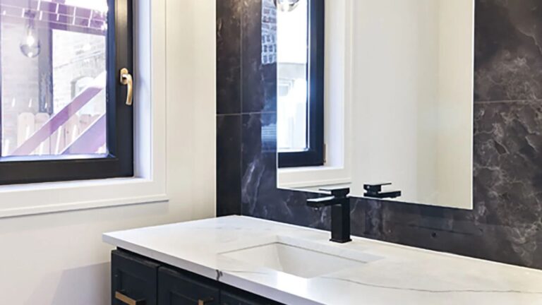 Modern bathroom vanity with dark blue cabinets and gold hardware.